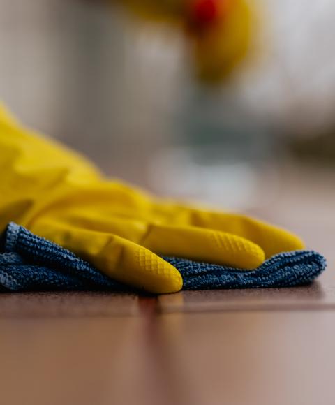 gloved hand wiping down a table