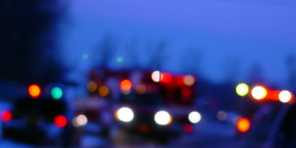 Blurred view of ambulance and police cars at a crime scene.