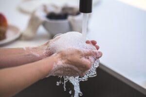 two hands washing with suds under a faucet