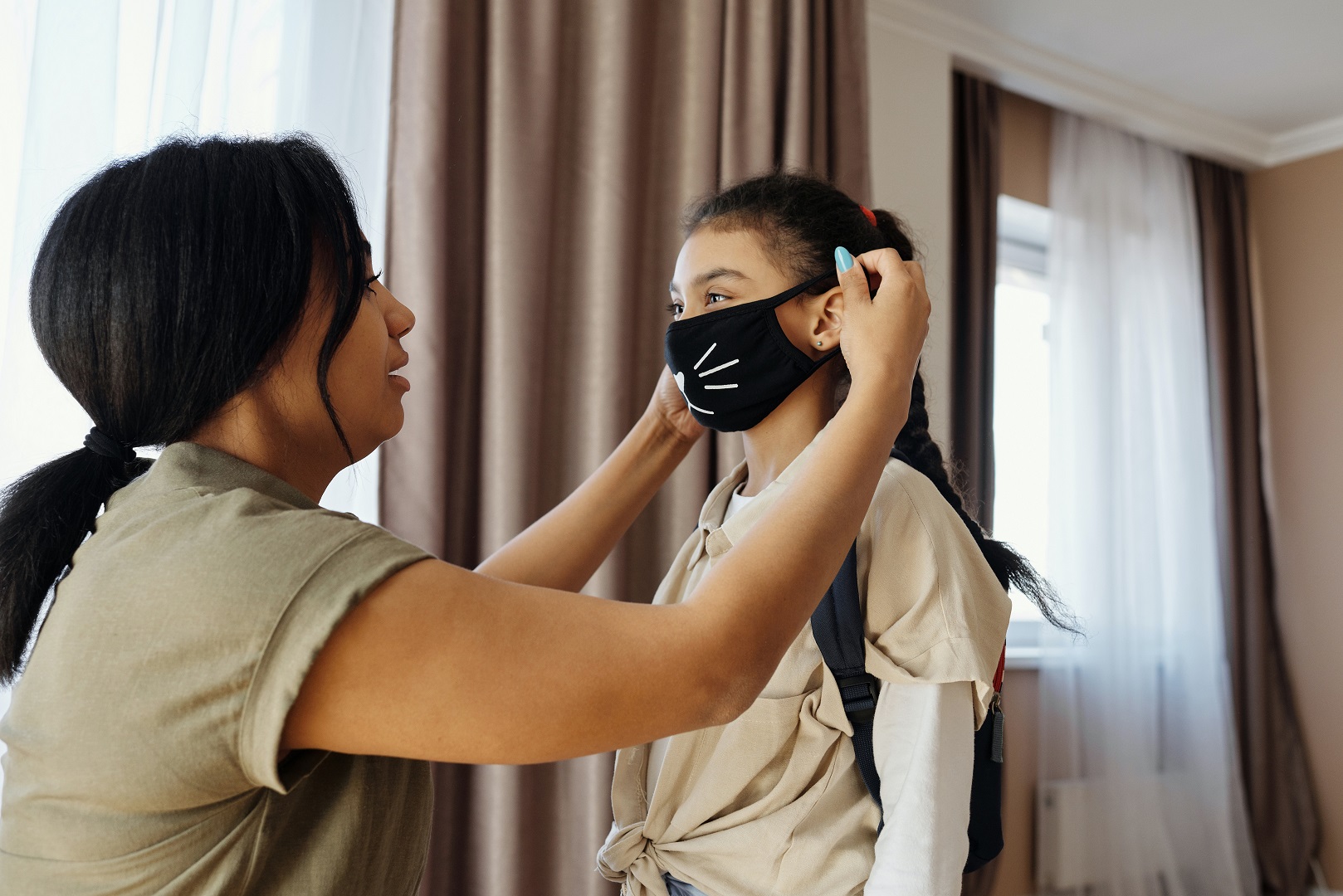 parent helping their child put on a facemask